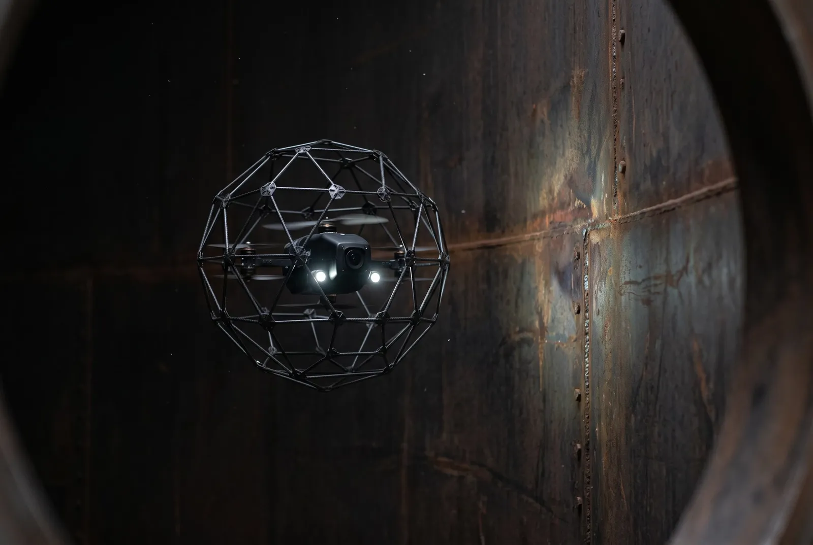 Dron con jaula protectora e iluminación propia vuela dentro de un estanque metálico